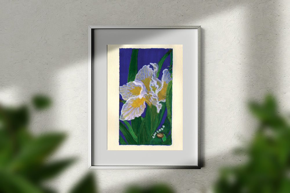 A framed painting of white and yellow irises on a deep blue background, mounted on a textured white wall with soft shadows and blurred green foliage in the foreground.
